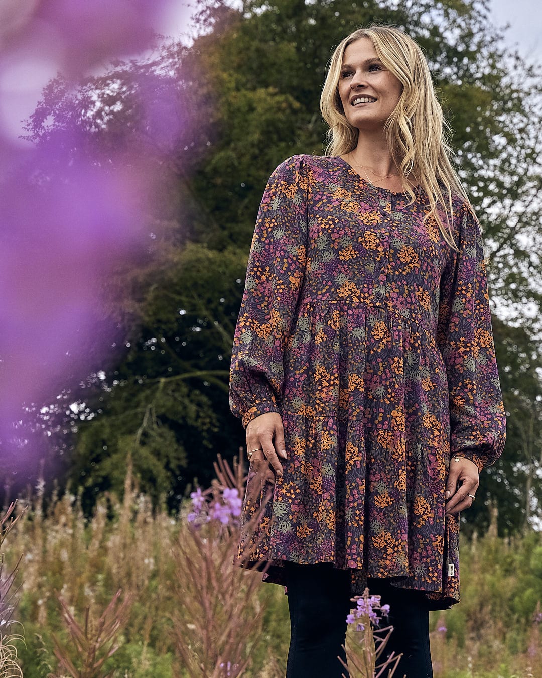 A woman in a Saltrock Garnet Womens Short Dress - Orange standing in a field.