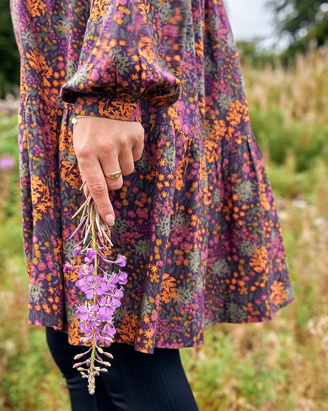 A woman holding a Garnet - Womens Short Dress - Orange from Saltrock in her hand.