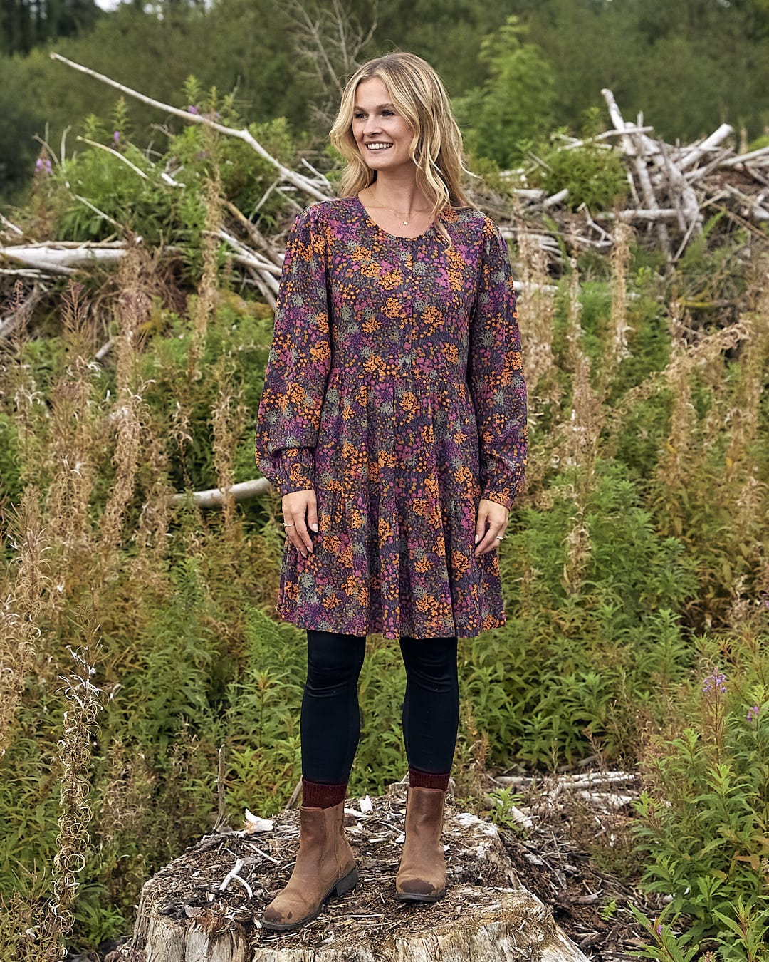 A woman in a Saltrock Garnet - Womens Short Dress - Orange standing on a stump.
