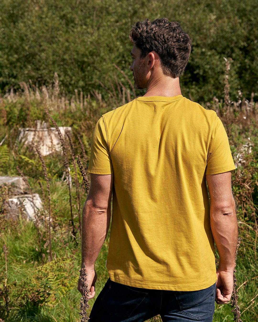 A man in a Saltrock Geo Peak - Mens Short Sleeve T-Shirt - Yellow standing in a field.