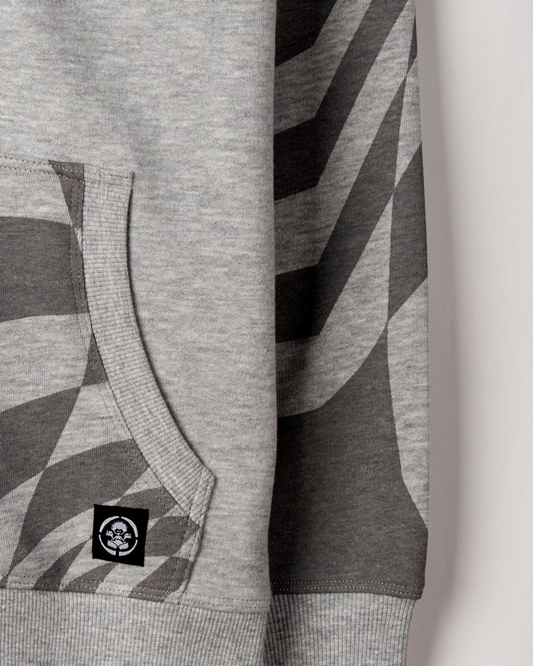 Close-up of a grey geometric print Saltrock Grip It - Kids Oversized Zip Hoodie with a visible pocket and brand tag.