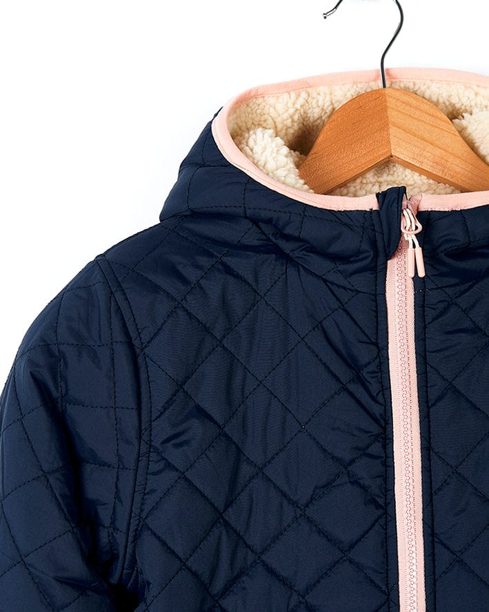 A Hadleigh - Reversible Coat - Blue/Cream by Saltrock with fur lining hanging on a hanger.