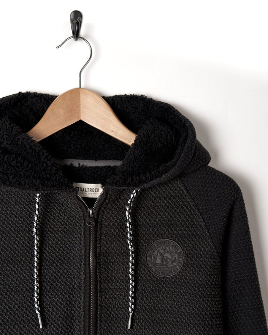 A black Hall - Borg Lined Hoodie by Saltrock hanging on a hanger.