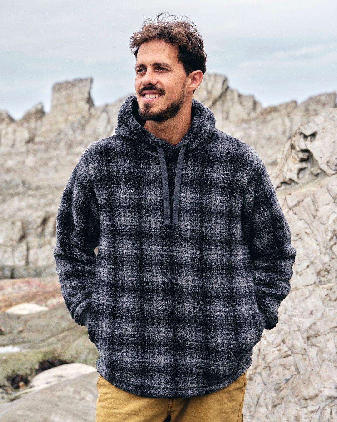 A man wearing a Saltrock Halycon - Mens Fleece Hoodie - Dark Grey, made of fleece material, with Saltrock branding.