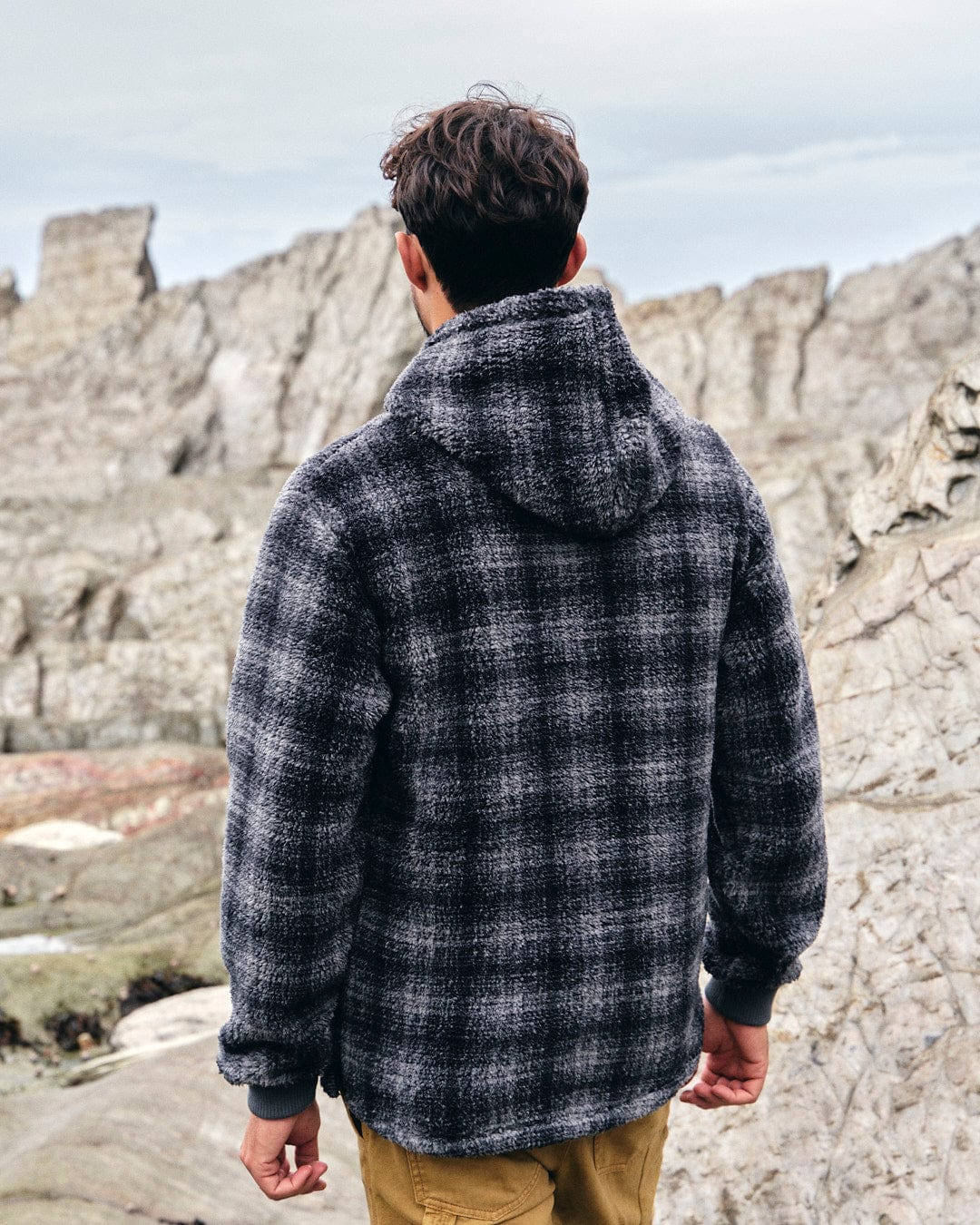 The back of a man wearing a Saltrock Halycon - Mens Fleece Hoodie - Dark Grey jacket.