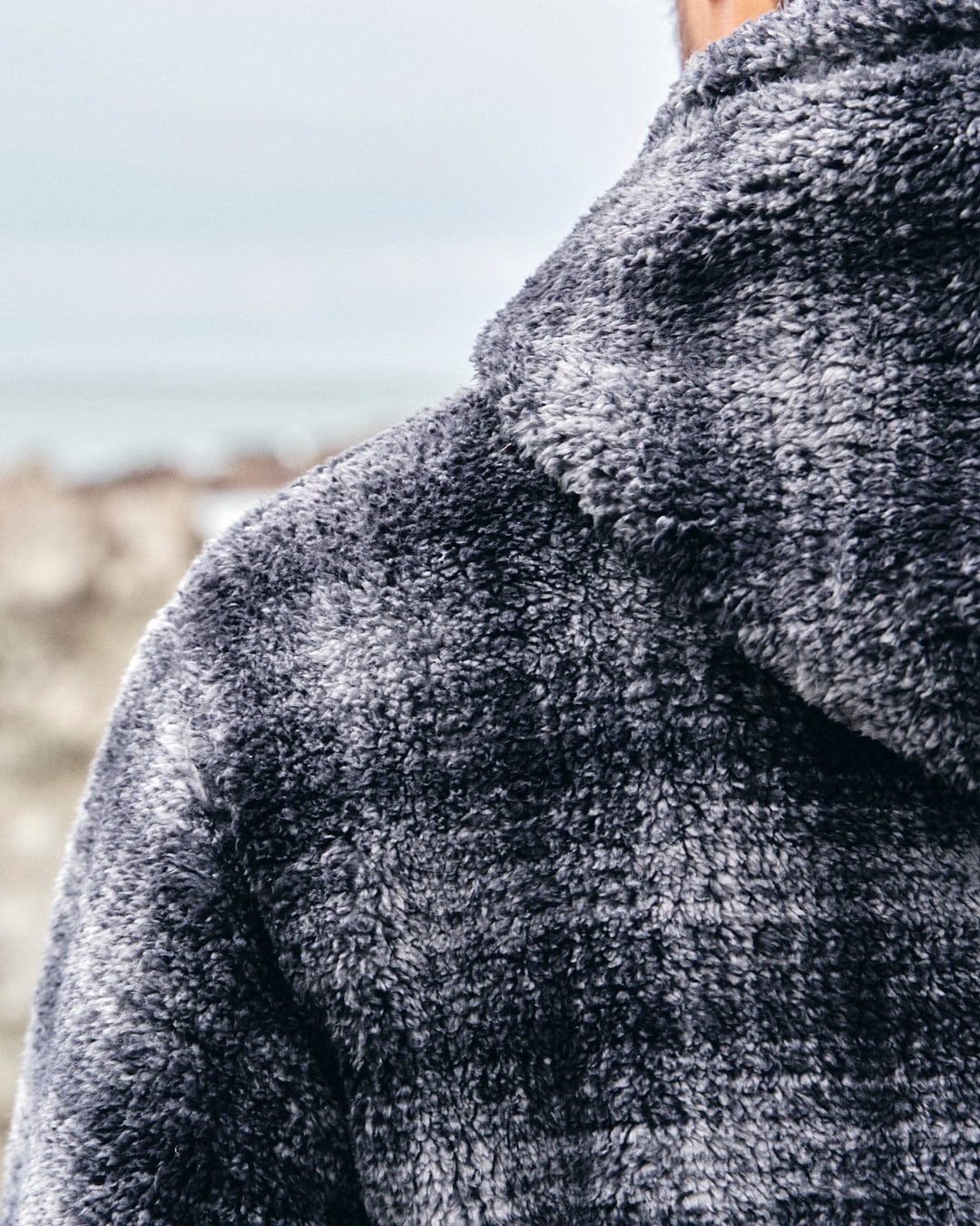 The back of a man wearing a Saltrock Halycon - Mens Fleece Hoodie - Dark Grey made of fleece material.