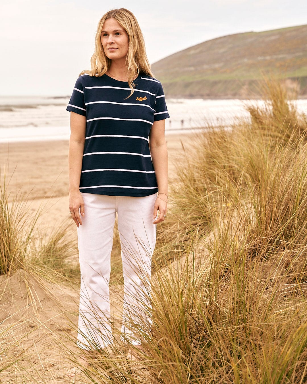 A woman standing on the beach wearing a Saltrock - Hartland Womens Striped Short Sleeve T-Shirt in Blue.