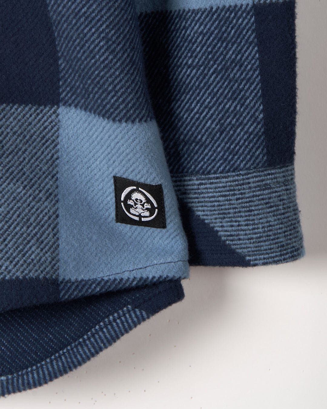 Close-up of a Saltrock Hawkins - Hooded Long Sleeve Check Shirt - Blue with a branded patch and pockets.