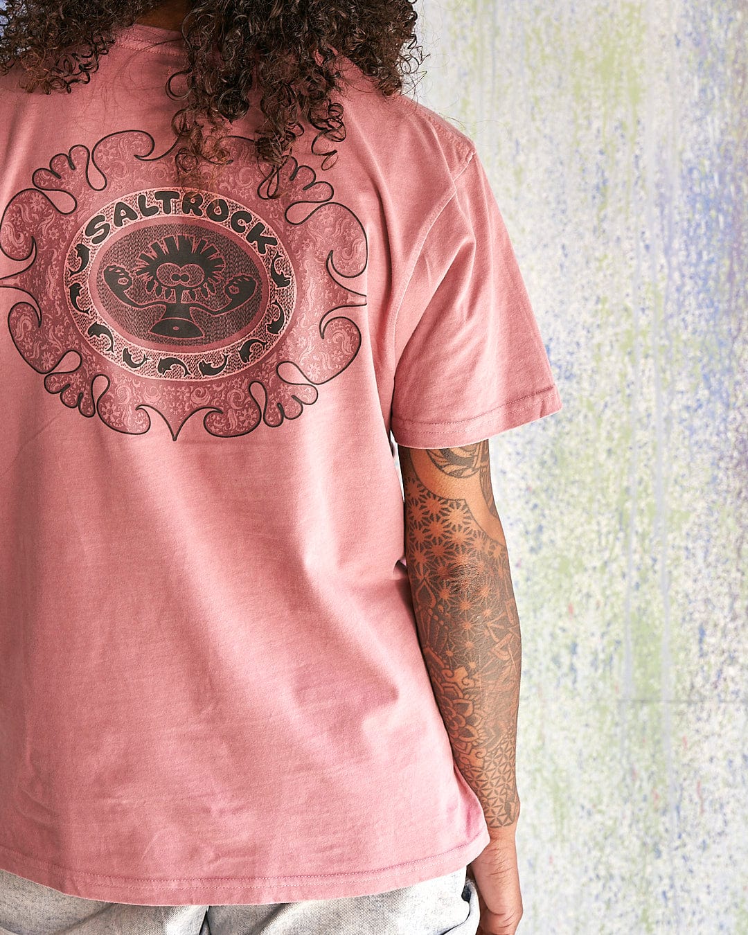 The back of a woman wearing a Saltrock Heraldic Tok - Limited Edition 35 Years T-Shirt t-shirt.