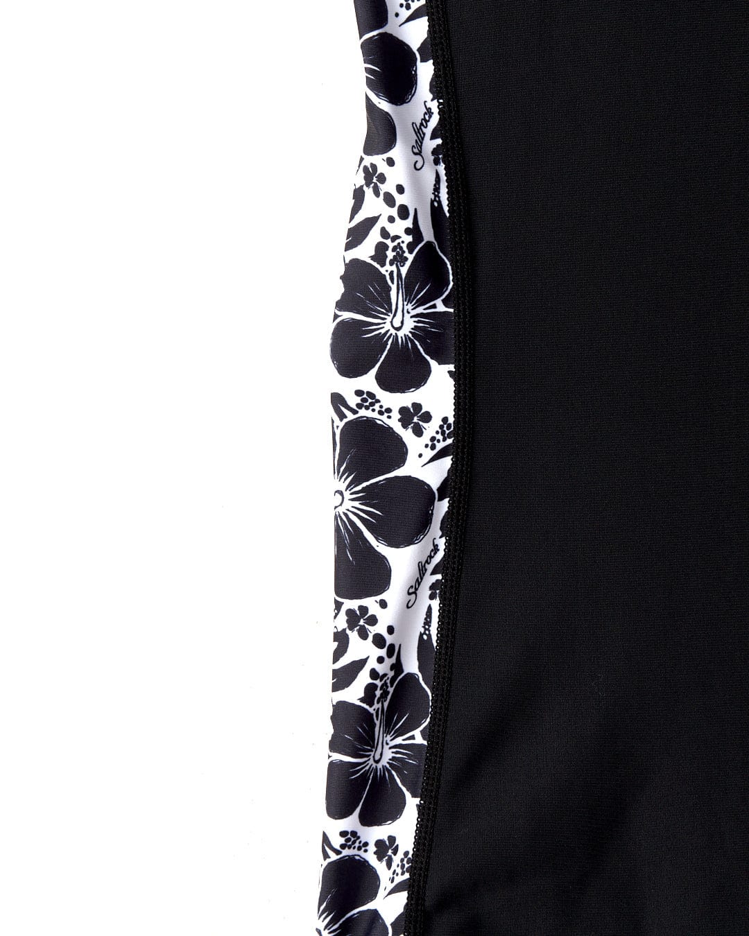 Close-up of a black and white Saltrock Hibiscus - Recycled Womens Short Sleeve Rashvest fabric panel next to a solid black fabric, separated by a vertical zipper.