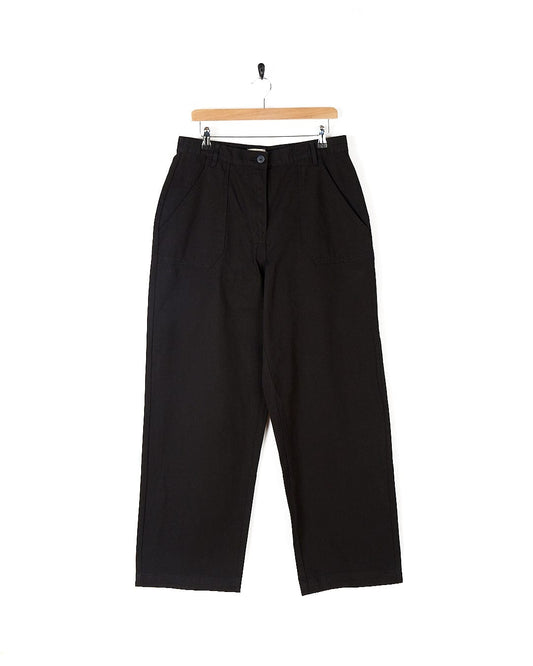 A pair of Hilda Twill - Womens Trouser - Black pants hanging on a hanger, branded by Saltrock.