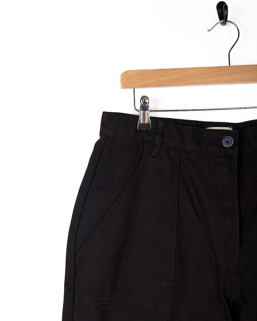 A pair of Hilda Twill - Womens Trousers - Black by Saltrock hanging on a hanger.