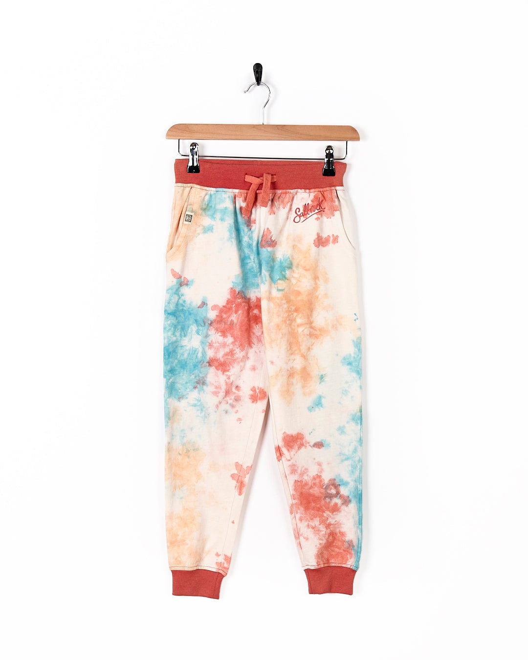A child's Saltrock Hippy - Kids Tie Dye Jogger - Multi pants hanging on a hanger.