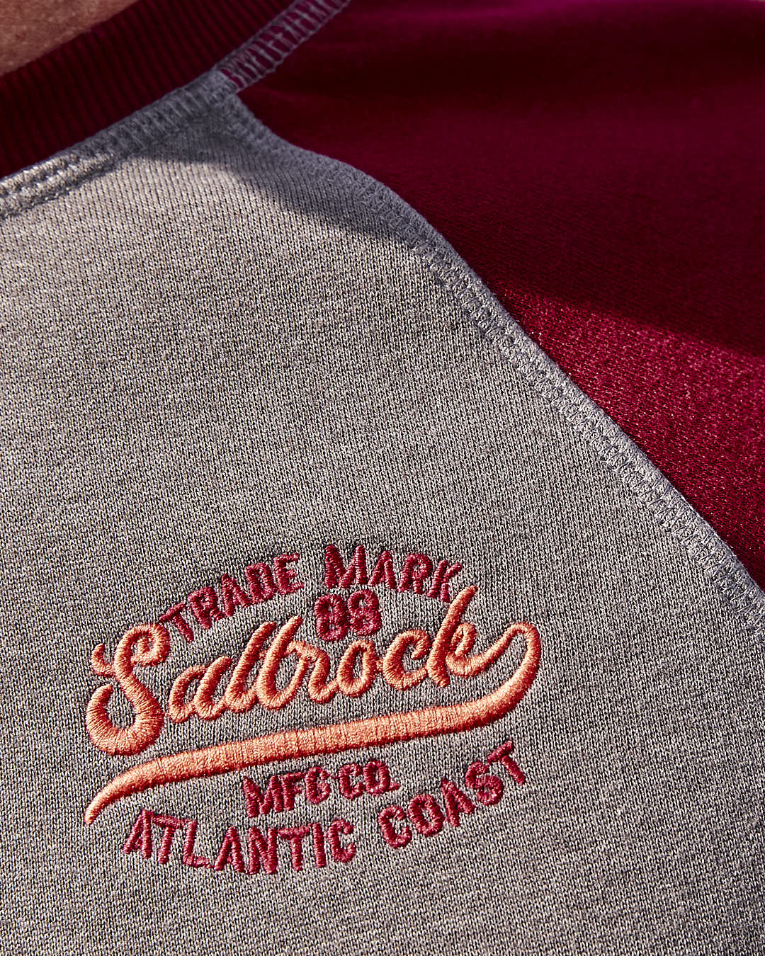 A man wearing a Saltrock Home Run - Mens Long Sleeve Sweat - Grey/Red with raglan-style and contrasting red sleeves.