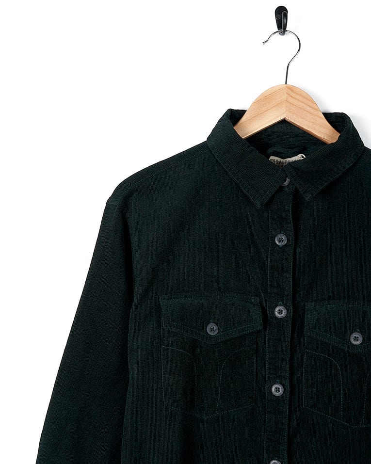An Iris - Cord Shirt Dress - Dark Green by Saltrock hanging on a hanger.