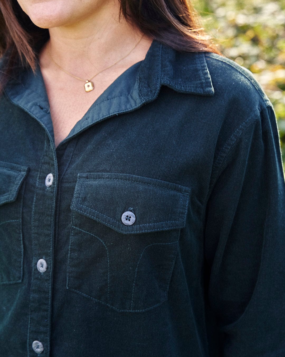 A woman wearing an Iris Cord Shirt Dress - Dark Green with Saltrock embroidery.