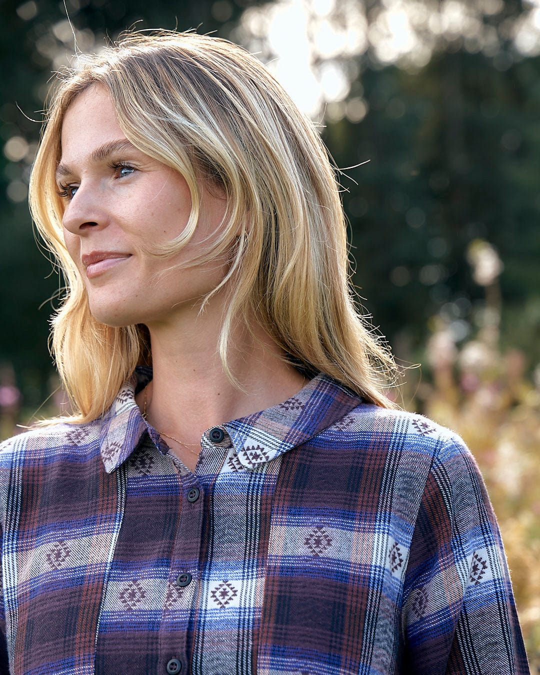 A woman is standing in a field wearing an Ivy - Womens Jacquard Check Shirt Dress - Purple from Saltrock with a flattering silhouette.