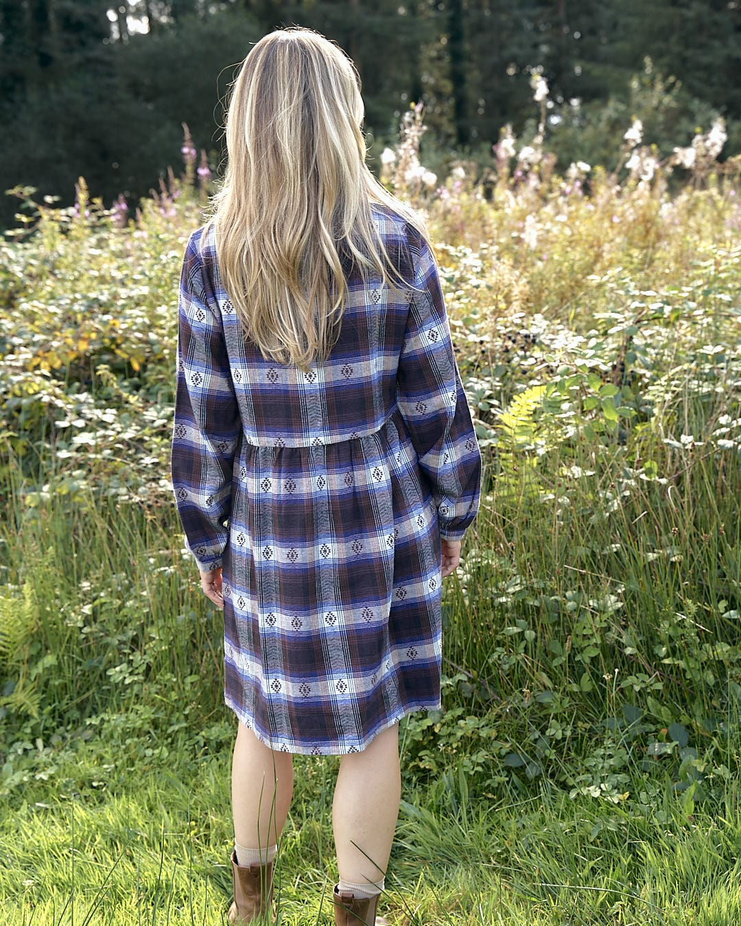 The back of a woman in a Saltrock Ivy - Womens Jacquard Check Shirt Dress - Purple standing in a field.