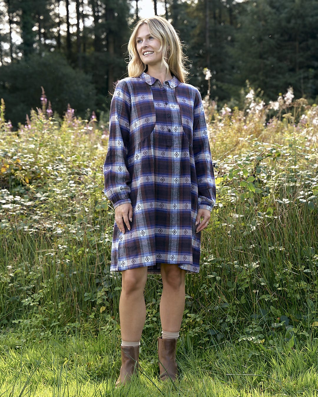 A woman in a Saltrock Ivy Womens Jacquard Check Shirt Dress - Purple standing in a field.