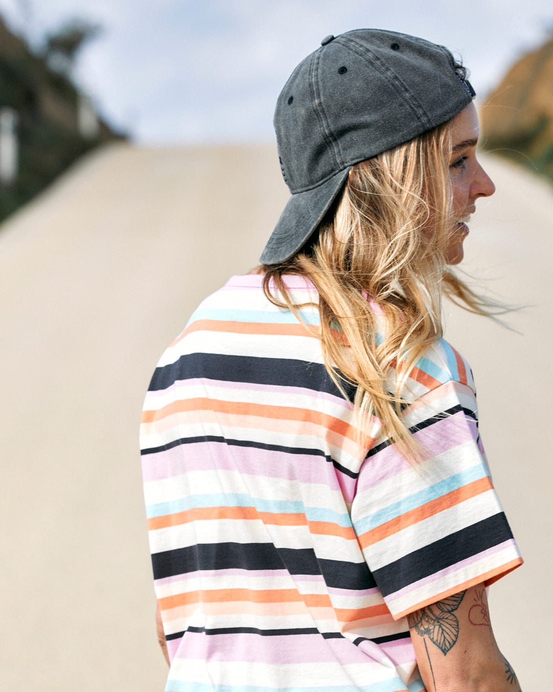 Person with a backward cap and Saltrock Juno Womens Short Sleeve T-Shirt - Multi standing outdoors, looking to the side.