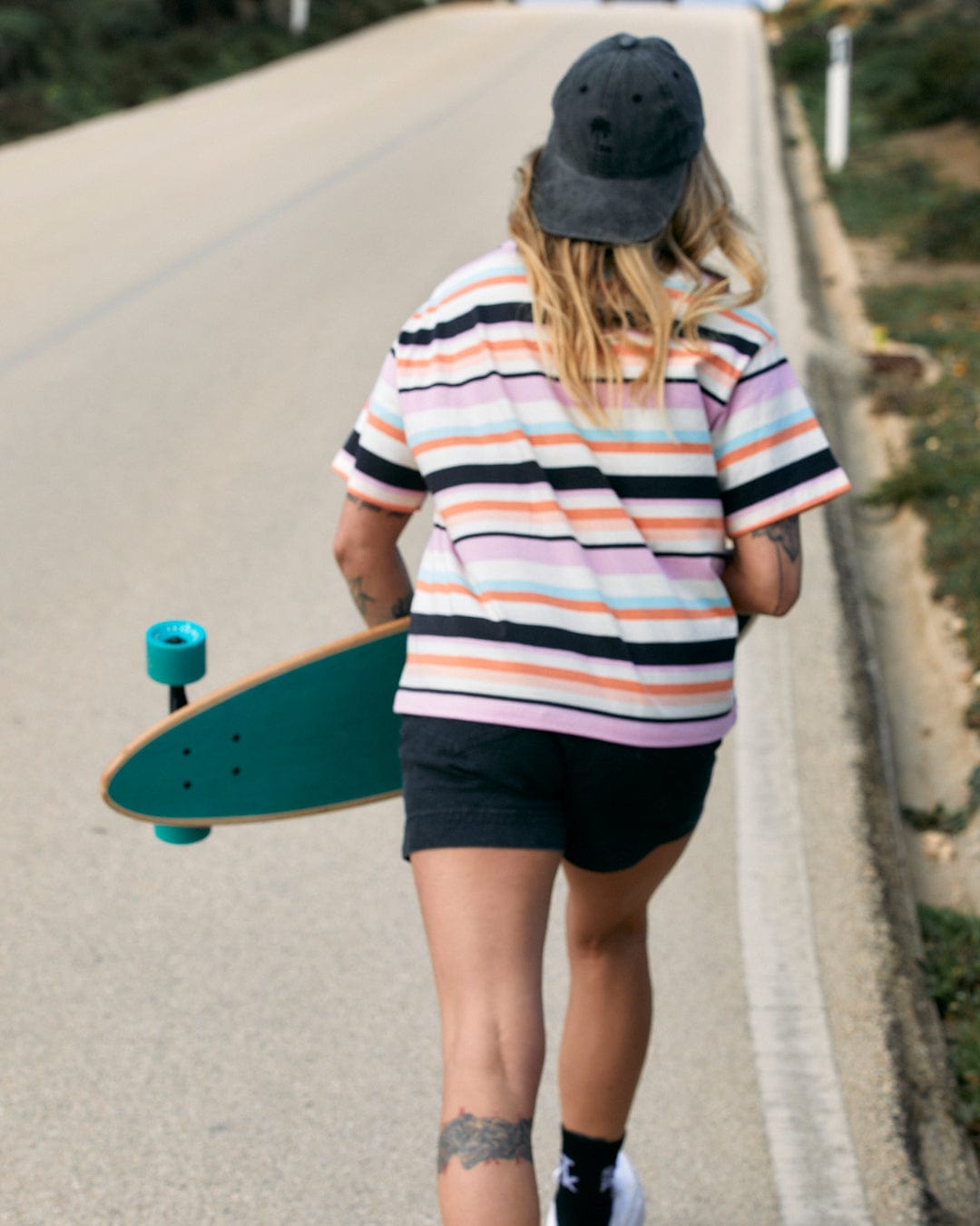 Person walking with a Saltrock Juno Womens Short Sleeve T-Shirt - Multi on a roadside, carrying a cotton bag with stripe pattern.