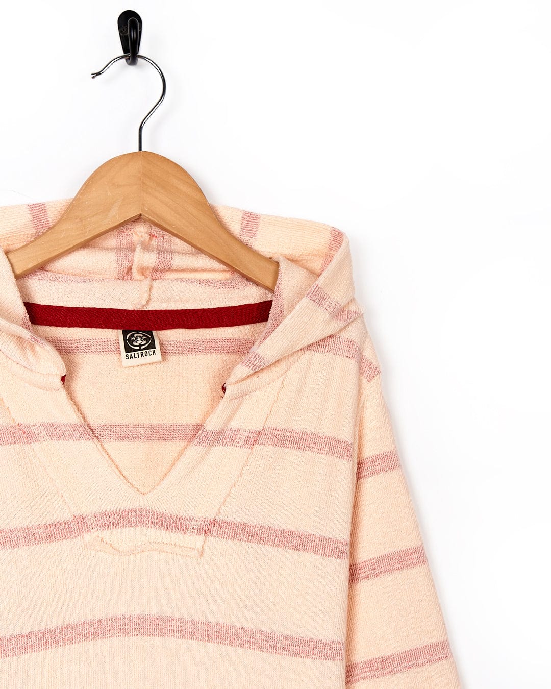 A Kennedy - Kids Pop Hoodie - Coral, from Saltrock, hangs on a wooden hanger.