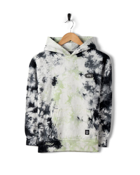 A Saltrock Las Vegas Smackdown - Kids Glow in the Dark Oversized Pop Hoodie - Multi with a blend of black, white, and light green patterns hangs on a wooden hanger against a plain white background. The hoodie features a cozy kangaroo pocket and a logo patch accentuating its unique style.