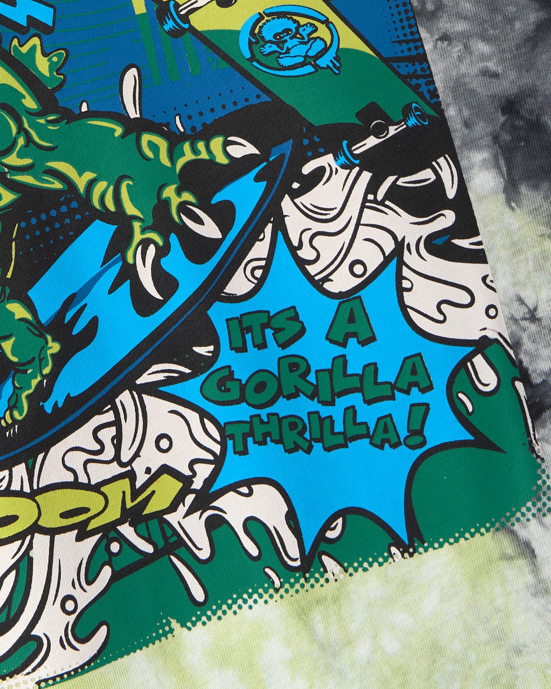 A colorful graphic of a green gorilla riding a Saltrock skateboard with tie dye patterns and the text "It's a gorilla thrilla!" on the side, all featured on the Las Vegas Smackdown - Kids Glow in the Dark T-Shirt - Multi by Saltrock.