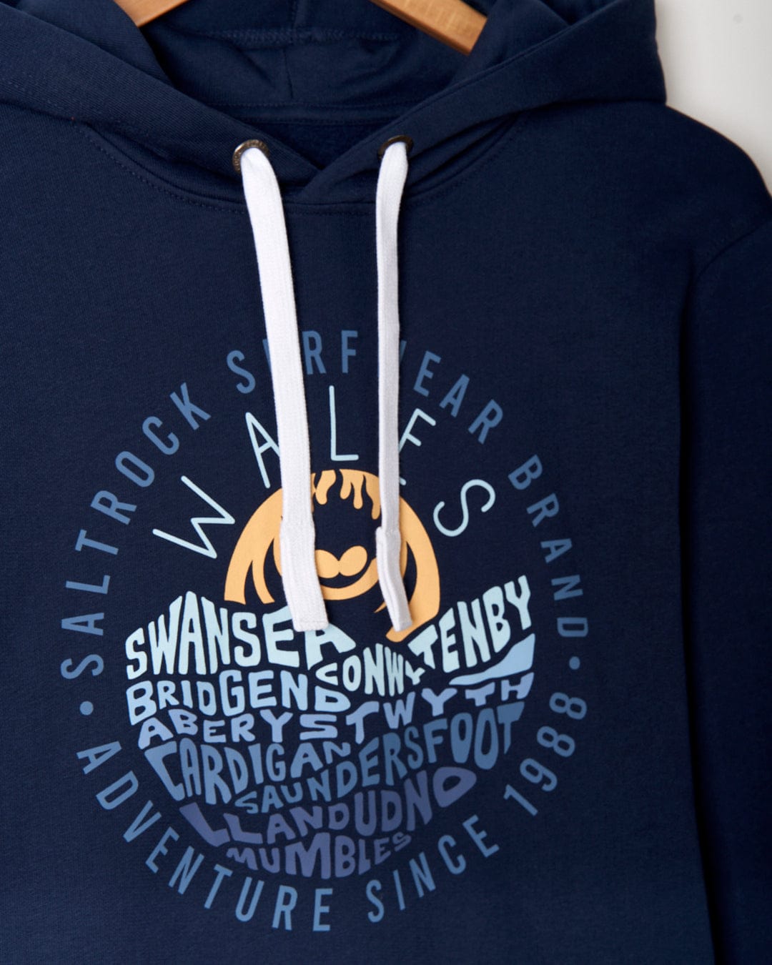 A blue cotton hoodie with the words Swansea and Wales in a chest print can be found in the Layers Wales - Mens Pop Hoodie - Blue by Saltrock.