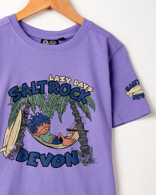 A purple cotton t-shirt that features the Lazy Location Devon Kids T-Shirt by Saltrock logo.