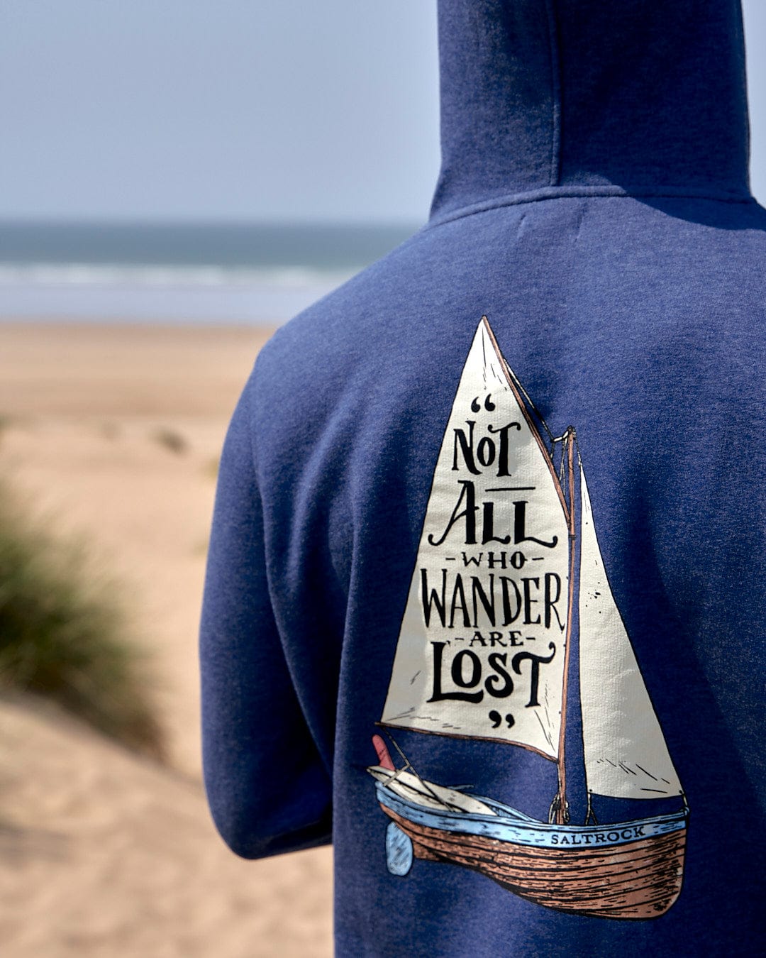 A man wearing a Saltrock hoodie with the Lost Ships - Mens Pop Hoodie - Dark Blue on it.