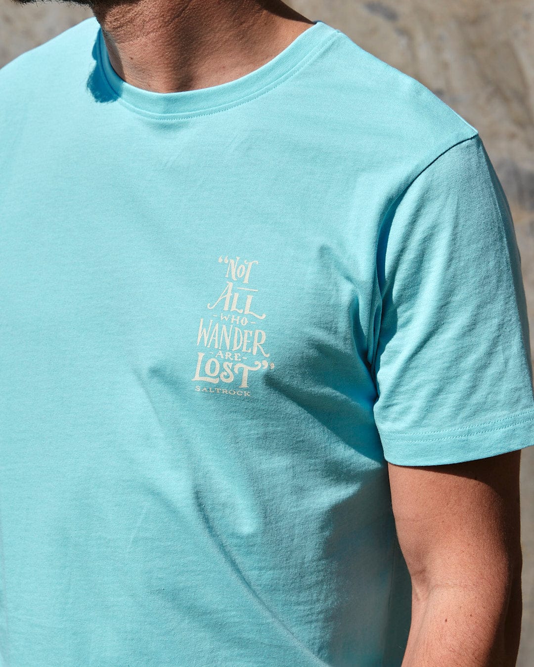 A man wearing a Lost Ships - Mens Short Sleeve T-Shirt - Turquoise by Saltrock with branding on it.
