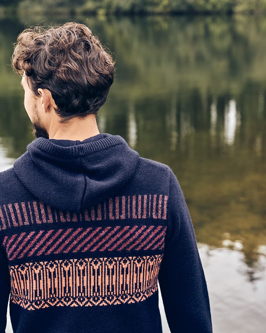 The back of a man wearing a Saltrock Lukas - Mens Knitted Hoodie near a body of water.