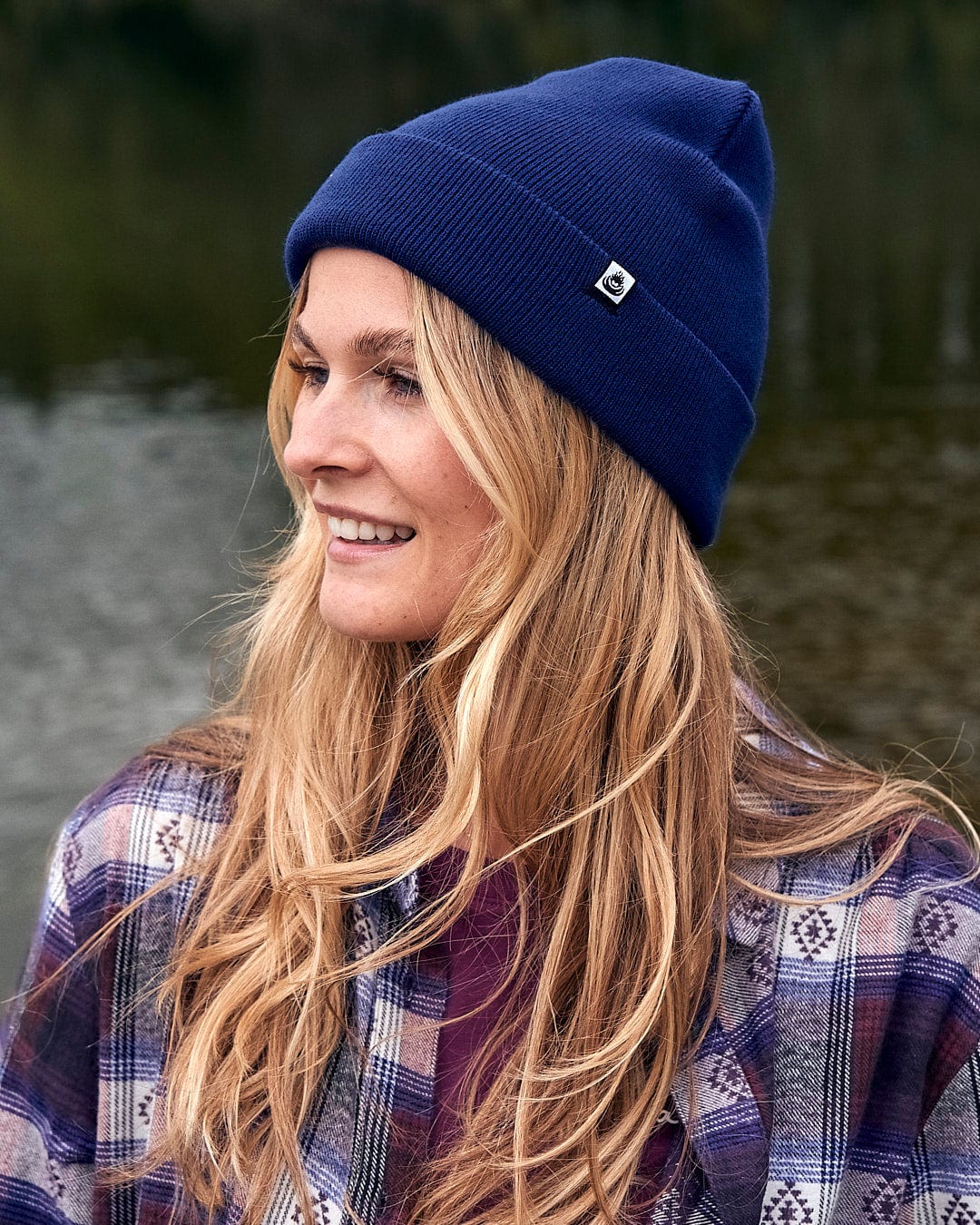 A woman in a plaid shirt wearing a Saltrock Ok - Tight Knit Beanie - Dark Blue.