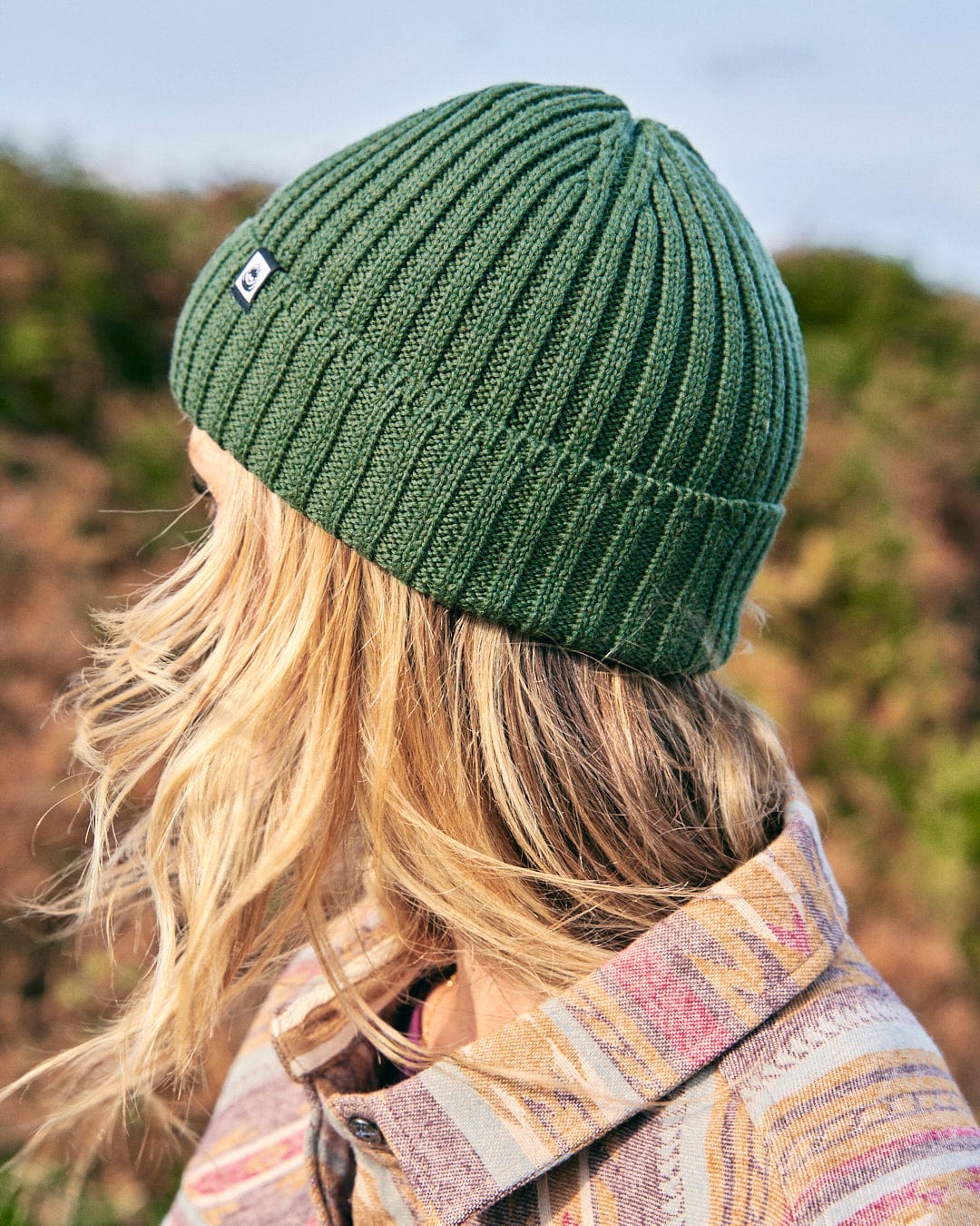 A Saltrock Maine - Fisherman Beanie - Green on an orange background.