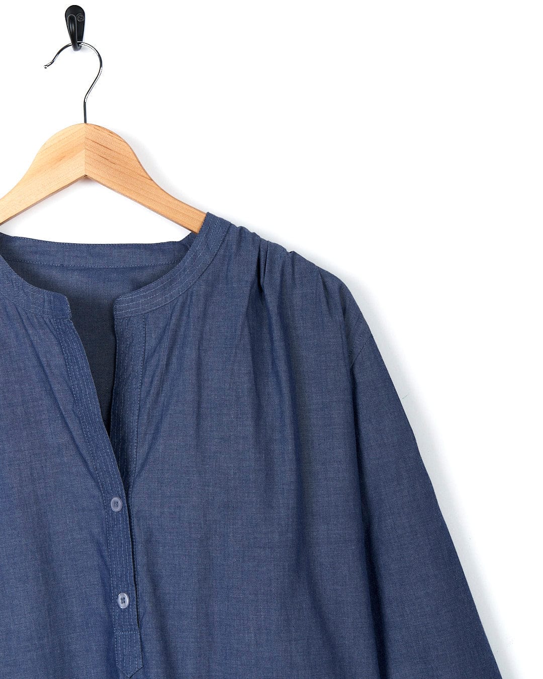 A Manina - Womens Beach Shirt - Blue hanging on a wooden hanger.