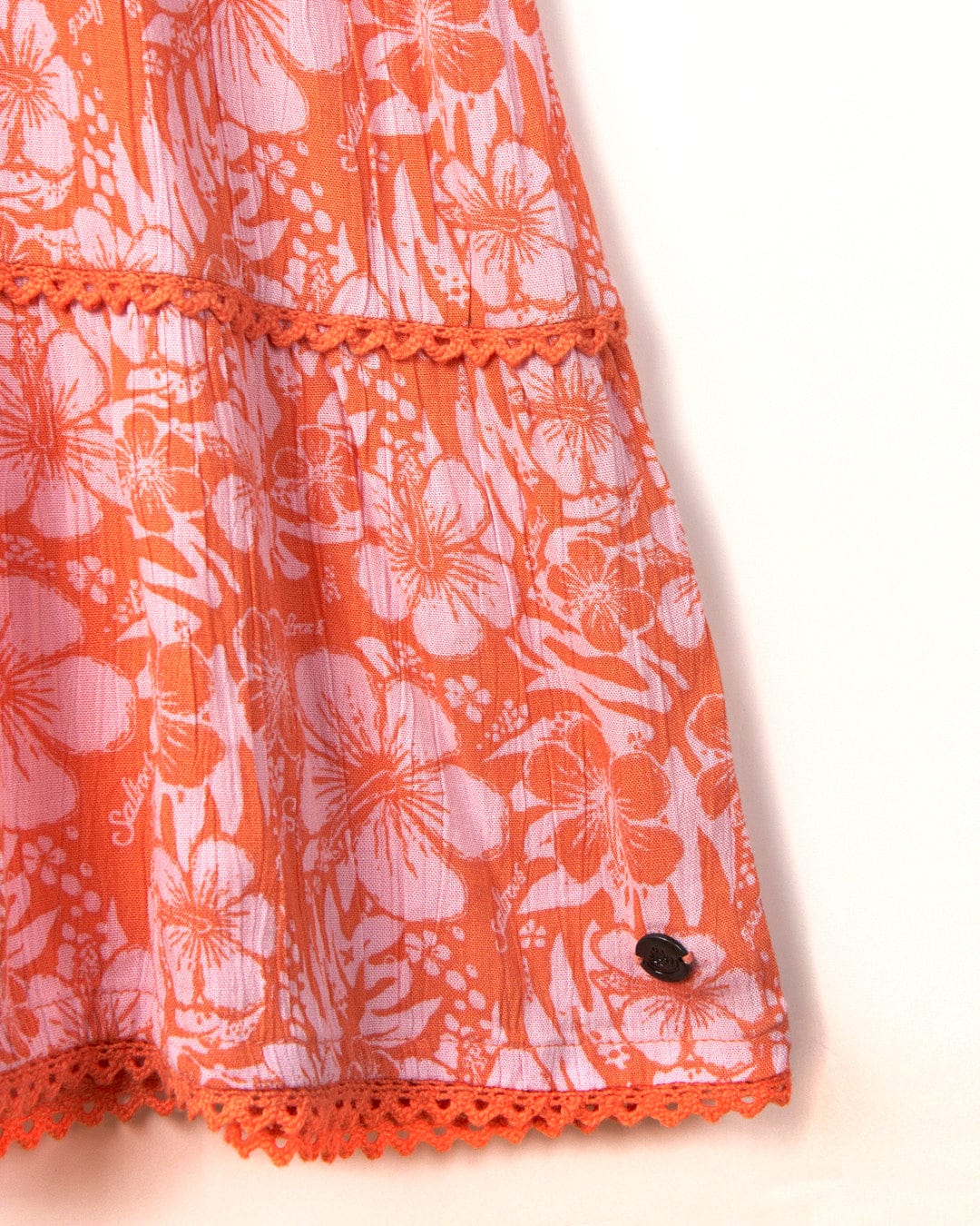 Saltrock's Marla Hibiscus Womens Dress in orange, with a coral-colored lace design and a small black button on a light background.