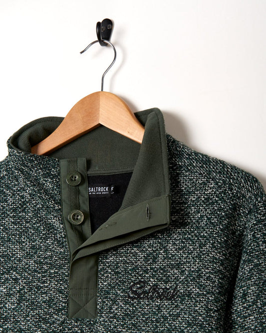 A textured Saltrock Meddow - 1/4 Neck Sweatshirt - Dark Green sweater hanging on a hanger.