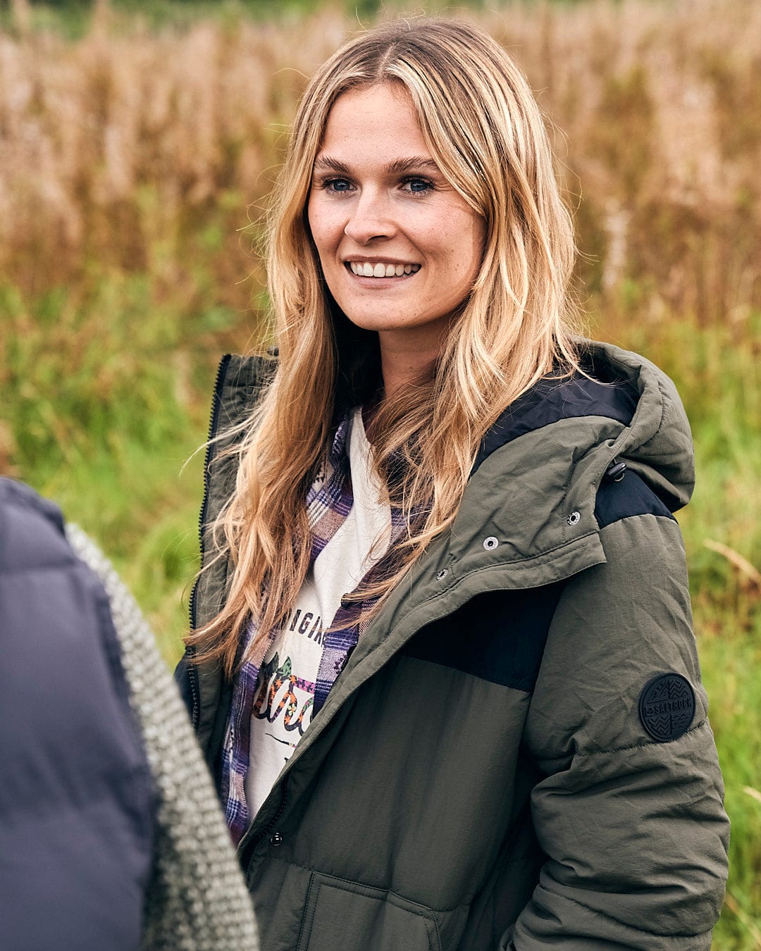 A woman in a Merle - Womens Puffer Jacket - Dark Green by Saltrock standing in a winter field.