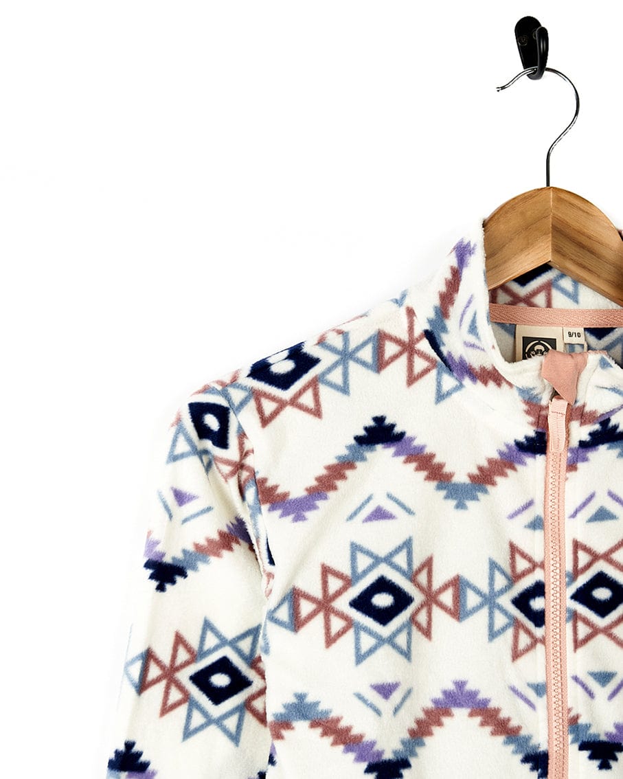 A women's Micro Ida - Kids Zip Fleece - Cream jacket by Saltrock, hanging on a hanger, providing warmth and comfort.