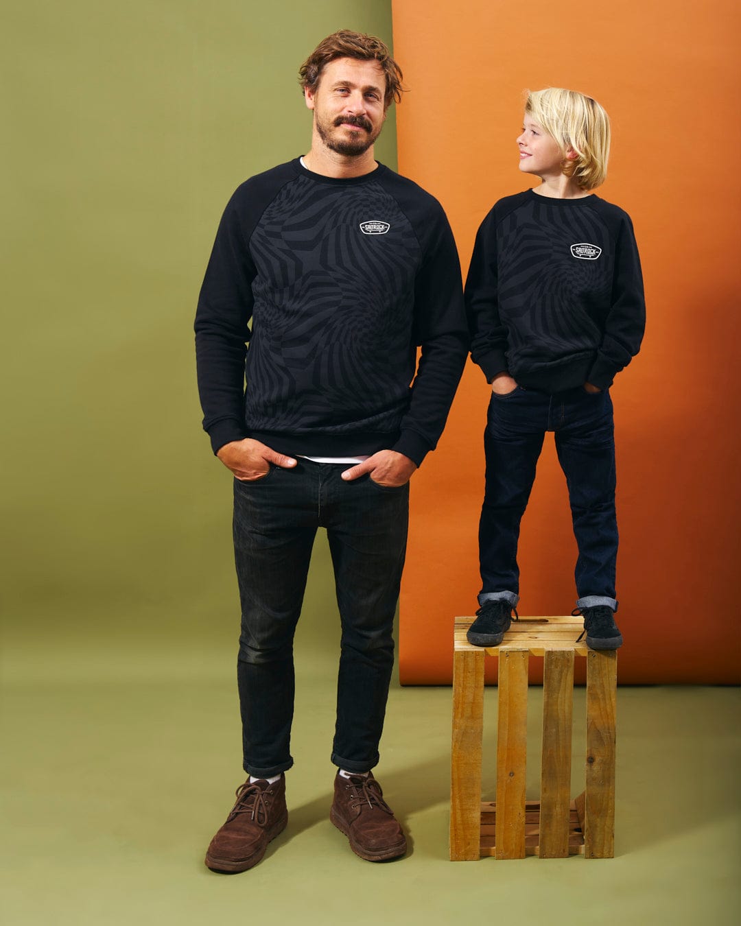 A man and a boy showcasing Saltrock branding on top of a wooden box featuring the Grip It - Kids Crew Neck Sweat - Black.