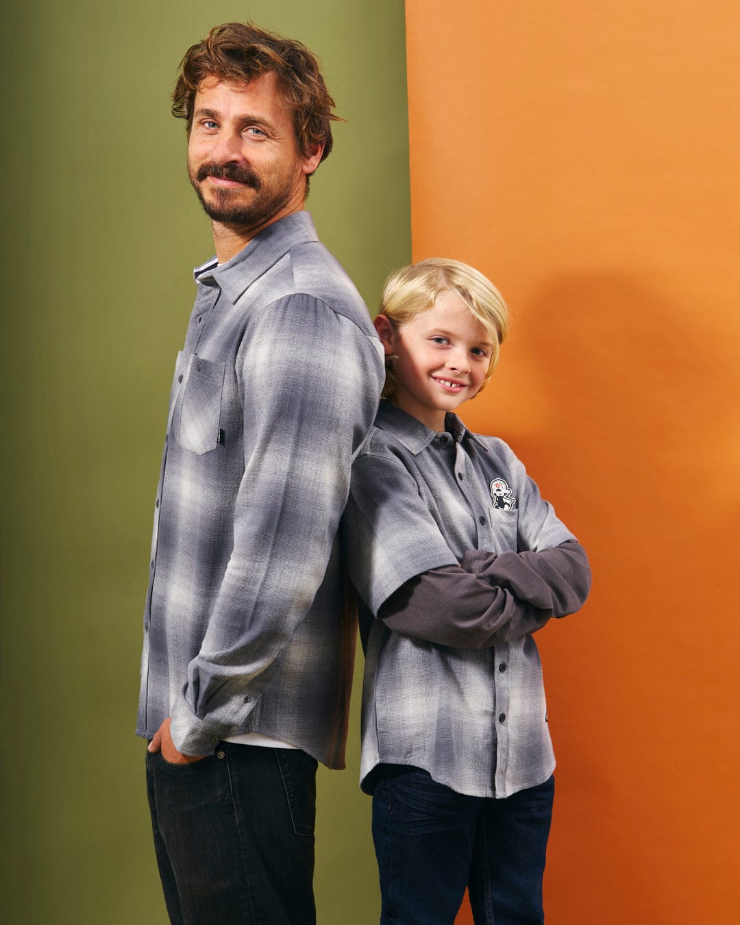 A man and a boy standing in front of an orange wall, wearing Saltrock's Farris - Mens Long Sleeve Check Shirt - Grey.