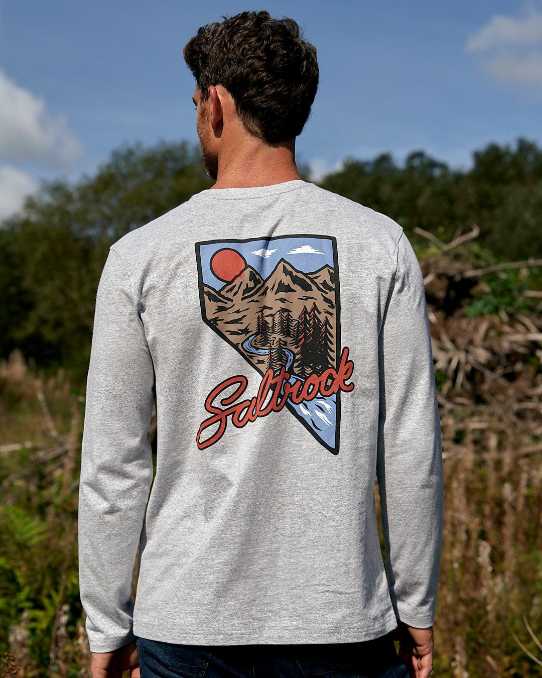 A man wearing a Saltrock Mountain Creek - Mens Long Sleeve T-Shirt - Grey with an image of a mountain.