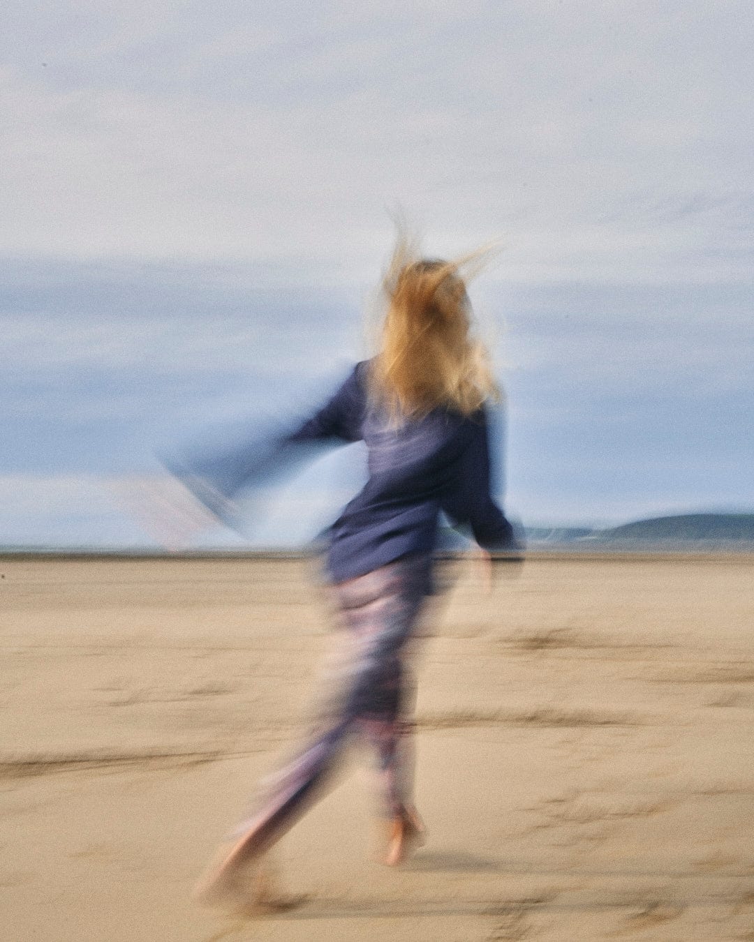 A woman running on the beach with a Saltrock - Mountain Rise Womens Flared Sleeve T-Shirt - Purple.