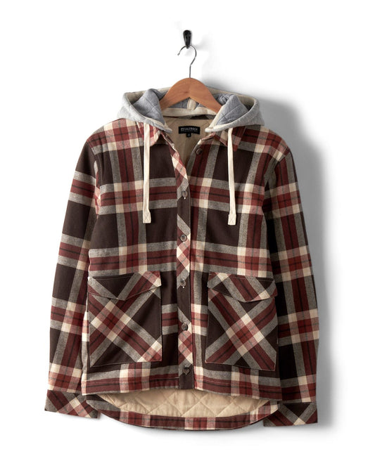The Saltrock Myla Women's Hooded Shacket in brown check features an oversized fit, large front pockets, a button-up front, and a detachable gray hood. Displayed on a wooden hanger against a white background.