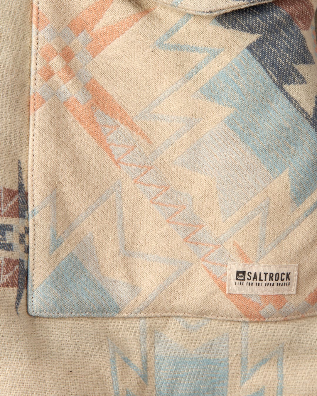 Close-up of a textured fabric with an Aztec pattern and a "Mylene - Aztec Shacket - Cream" label.