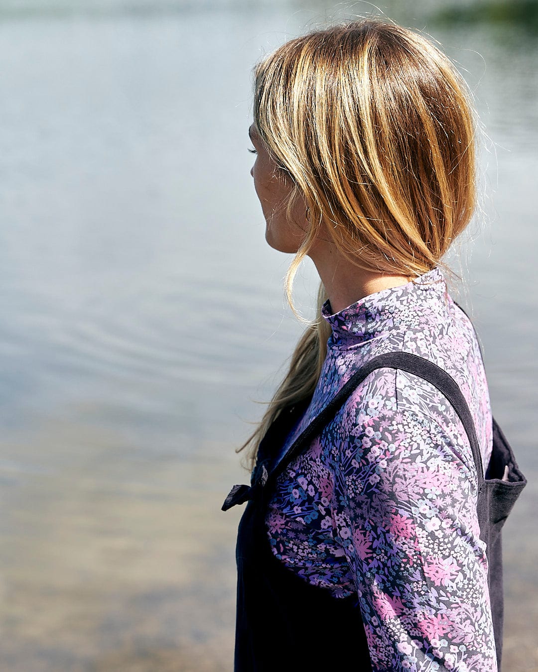 A woman is wearing a stylish Saltrock - Brooklyn Womens Long Sleeve T-Shirt - Purple while standing in front of a body of water.