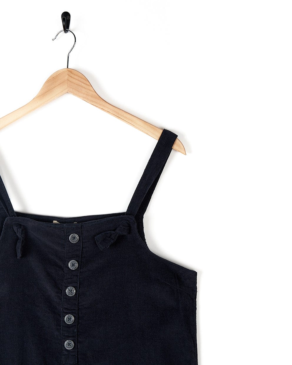 A stylish Saltrock Nancy - Womens Cord Dungaree - Dark Blue dress, made from dark blue cord material, hanging on a hanger.