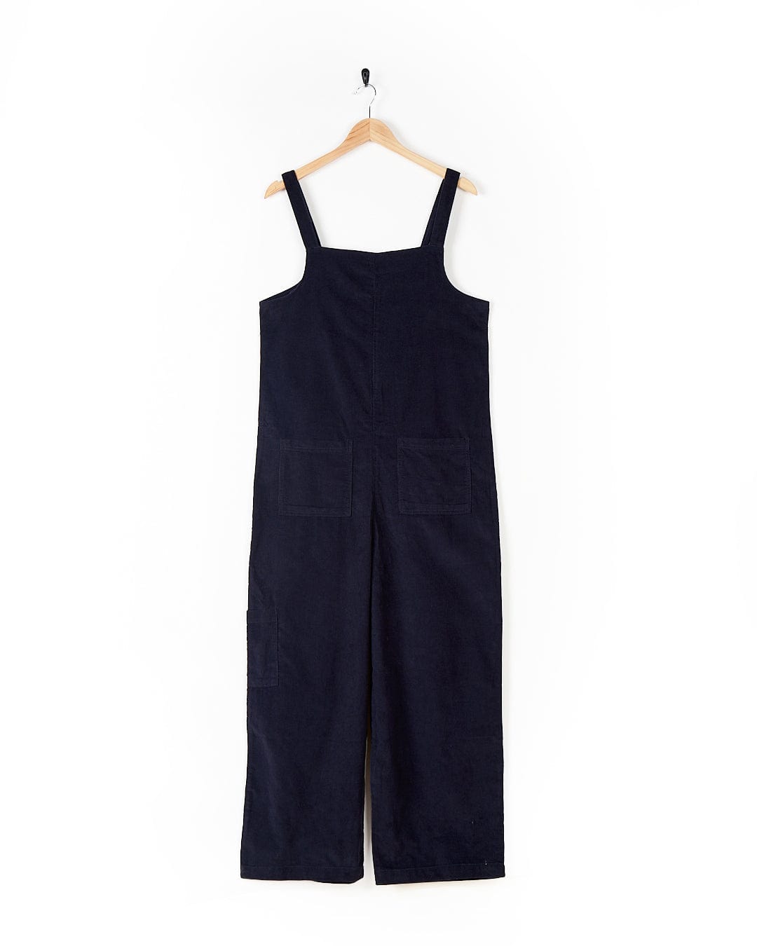 A Nancy - Womens Cord Dungaree - Dark Blue jumpsuit hanging on a hanger. (Saltrock)