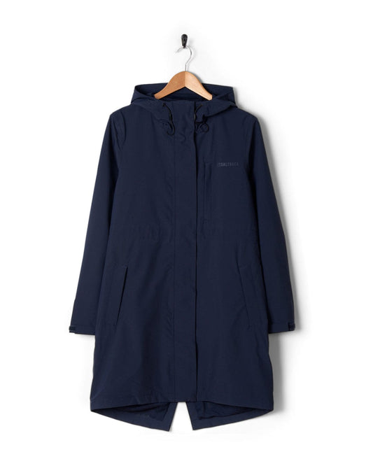 A Saltrock North West Womens Waterproof Jacket in Blue, with an adjustable hood, hanging on a wooden hanger against a white background. The jacket features a small logo on the chest.